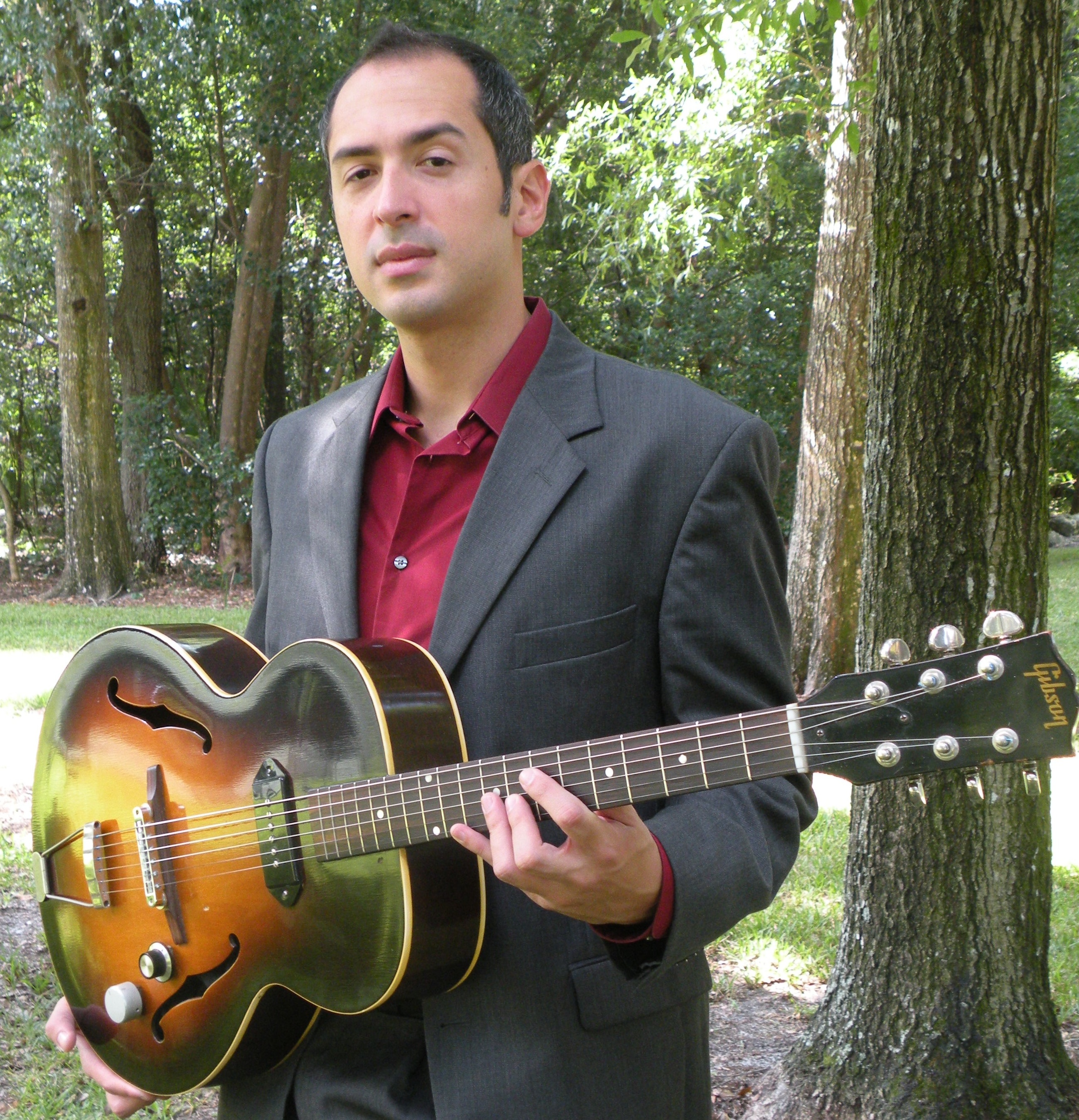 Carlos J. F. DeSoto holding a hollow-body guitar outdoors